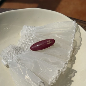 Close-up of dark red acetate hair clip with gold France Handmade lettering on lace