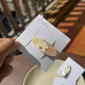 Elegant profile face acetate hair clip with pearl accents on a display card