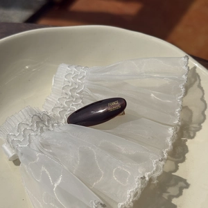 Detail of acetate tortoise shell hair clip with gold label on white lace background