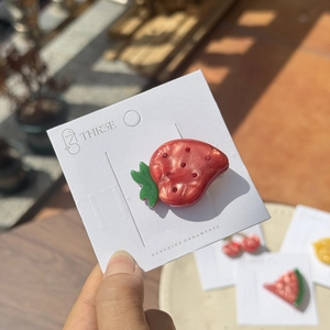 Sparkling strawberry hair clip made of acetate resin with red rhinestones on card