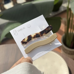 Close-up of tortoise shell and beige wave-shaped acetate hair clips on display card