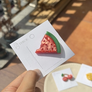 Detailed view of watermelon shaped resin hair clip with rhinestones on branded card