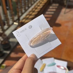 Barrette ovale en résine rose pailletée élégante sur une carte de présentation