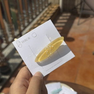 Détail d'une pince à cheveux ovale en résine jaune avec paillettes argentées