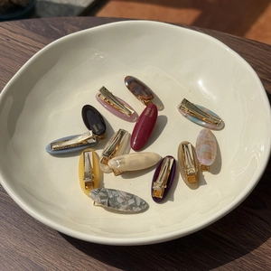 Macro detail of various acetate hair clips with elegant marble patterns and golden metal clips