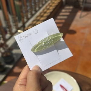 Gros plan d'une pince à cheveux vert clair pailletée sur une carte de présentation