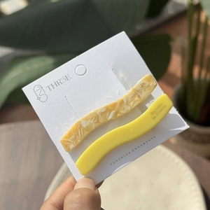 Elegant wavy acetic acid hair clips in yellow and marble pattern on a display card