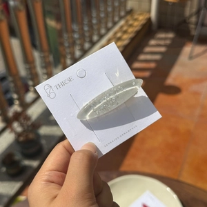 Vue macro d'une barrette transparente à paillettes argentées sur son emballage blanc