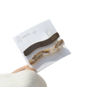 Elegant wavy acetate hair clips set in dark brown and amber marble with gold logo