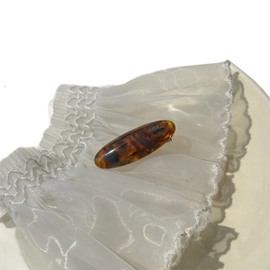 Elegant tortoise shell acetate hair clip with gold label on white lace background