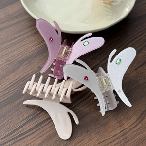 Close-up of three butterfly hair claws in glitter purple, white and beige acetate