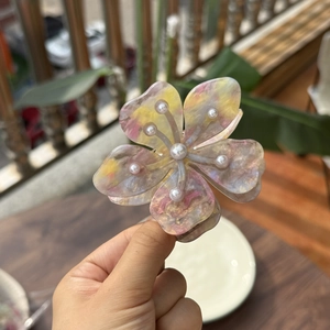 Détail d'une pince à cheveux fleurie avec motif marbré tie-dye et perles blanches