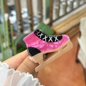 Macro detail of ice skate hair claw clip in pink marble acetate with golden blade finish
