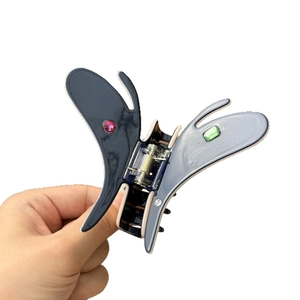 Butterfly acetate hair claw clip with colorful rhinestones in hand-held view