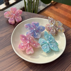 Détail de pinces à cheveux florales en acétate marbré avec perles blanches centrales