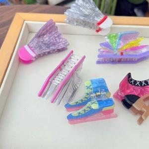 Detailed view of creative acrylic hair claws in badminton, skate, and book designs