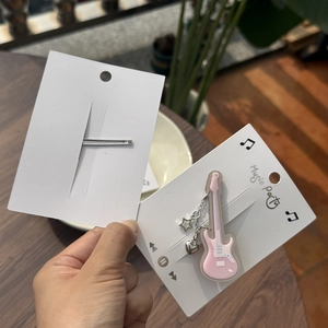 Détail de la pince à cheveux guitare en acrylique rose avec breloques cœur et étoile