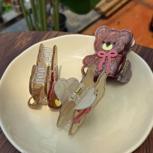 Trois pinces à cheveux ours en marron, ambre et crème avec nœuds roses sur plateau