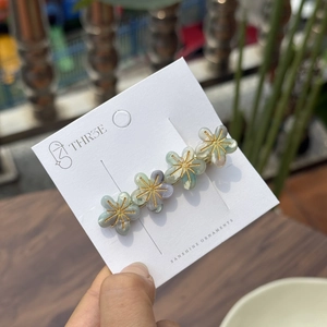 Haarklammer mit fünf Acetat-Blumen in Marmoroptik und goldenen Akzenten auf Karte