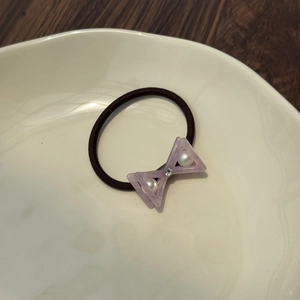 Detail of lavender bow hair tie with pearls and crystals on a white ceramic plate