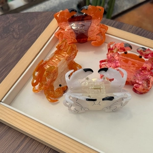 Detail view of four colorful crab-shaped hair claws on a tray in a set of vibrant tones