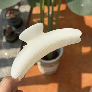 Minimalist creamy white crescent hair claw clip for women in natural outdoor lighting