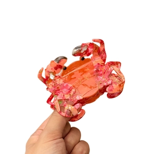 Crab-shaped acetate hair claw clip with vibrant orange floral patterns and gold details
