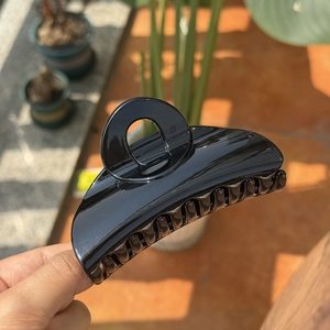 Close-up of a large glossy black hair claw clip with strong teeth for firm hold