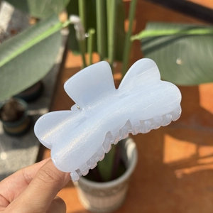 Détail d'une pince à cheveux papillon bleu clair avec finition pailletée tenue à la main