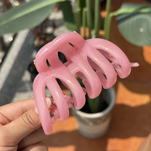 Sparkling pink resin hair claw clip with gold glitter in natural sunlight