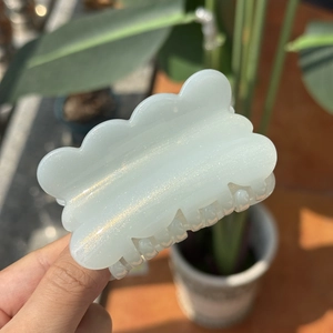 Close-up of cloud-shaped hair claw clip with pearlescent glitter finish in soft light