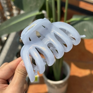 Detail of light blue glitter hair claw clip with pearlescent finish and secure metal spring