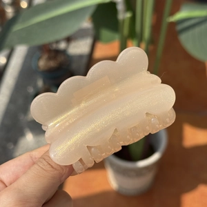 Cloud-shaped resin hair claw clip with gold glitter in beige, shown in sunlight detail