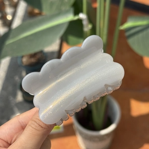 Detail of pearl white claw clip with shimmering glitter and wavy cloud-shaped design