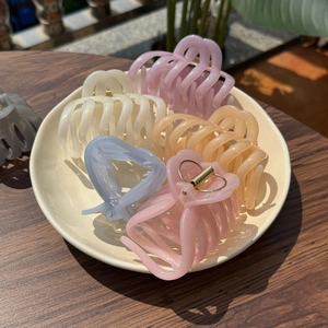 Close-up of matte resin claw clips in assorted macaron colors with golden metal springs