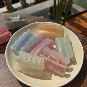 Detailed view of colorful glitter wave hair claws in pastel shades on a ceramic plate