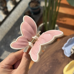 Pink and beige butterfly-shaped plastic hair claw clip with a matte resin finish