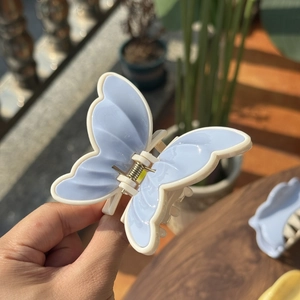 Detail view of a blue butterfly hair claw clip with a matte plastic finish and metal spring