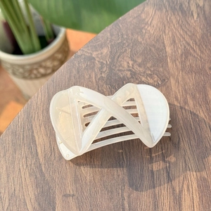Elegant cream-white X-shaped hair claw clip with a glossy finish and geometric design