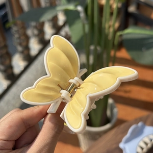 Detail of yellow and white butterfly hair claw clip with golden metal spring mechanism