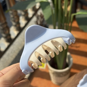 Detail of a large plastic shark hair claw clip in contrast light blue and cream white