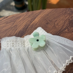 Mini floral cellulose acetate hair claw clip in light green with a central black dot detail