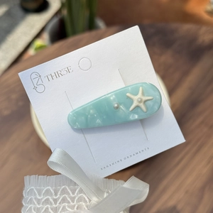 Pale blue marble acetate hair clip with starfish and pearl on a white display card