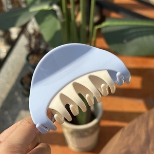 Detail showing contrast blue and cream plastic hair claw clip with interlocking teeth