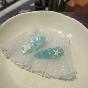 Close-up of blue marble pattern acetate hair clips with starfish and seashell details