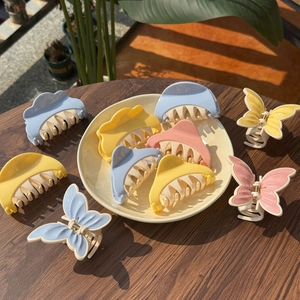 Close-up of pastel butterfly and cloud hair claws on wooden surface and ceramic plate