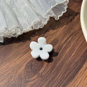 Mini acetate flower hair claw clip with white petals and a green gem on wooden background