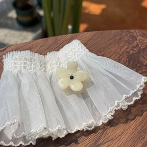 Close-up of white organza lace cuffs with embroidered edges and floral button accents