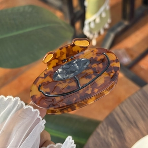 Pince à cheveux chien en acétate avec motif écaille de tortue tenue à la main