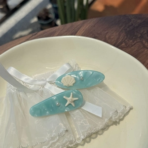 Close-up of light blue acetate hair clips with shell, starfish and pearl details
